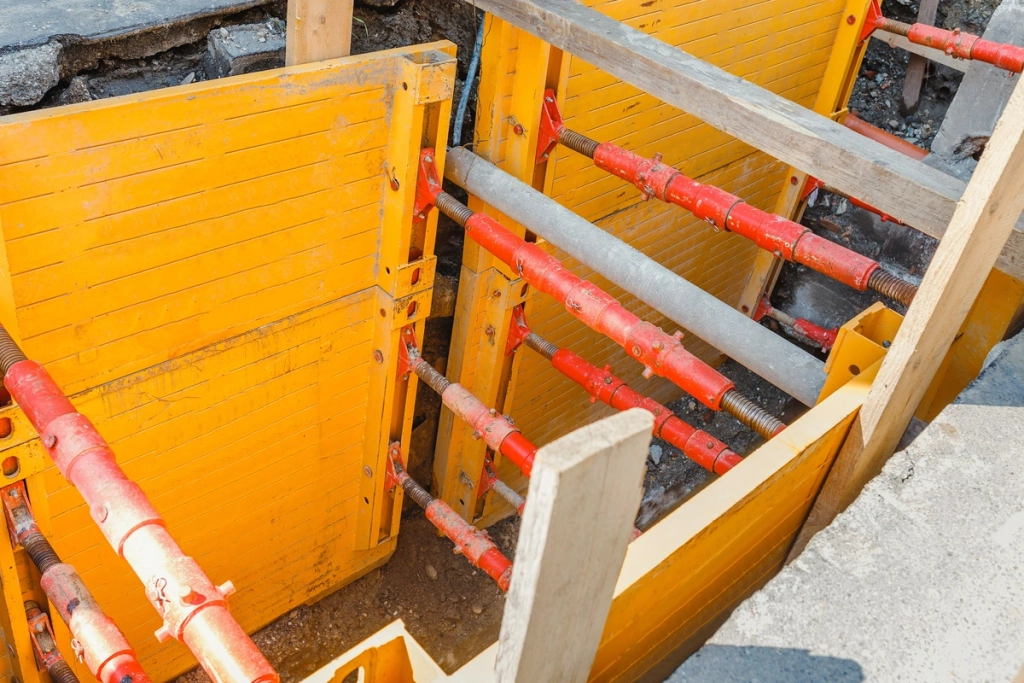 Chantier de travaux souterrains avec des soutènements métalliques et des étais rouges pour stabiliser les parois